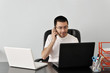 Photo: Young businessman working at his desk with two laptops Young businessman working at his desk with two laptops
