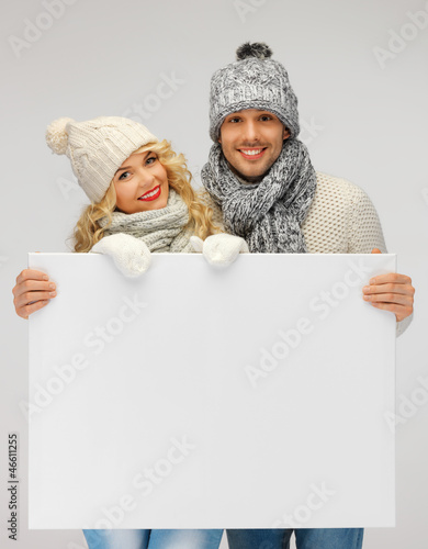 Photo: couple in a winter clothes holding blank board couple in a winter clothes holding blank board