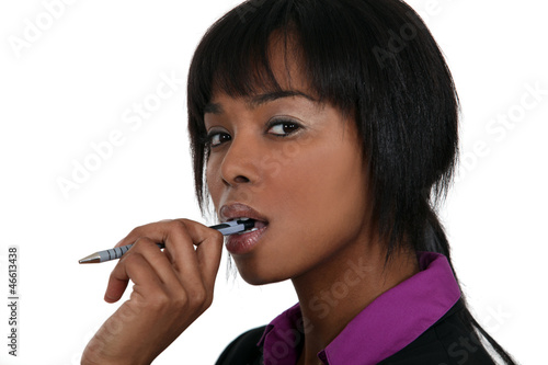 Photo: A pensive woman chewing on her pen A pensive woman chewing on her pen