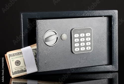 Photo: Money in open safe isolated on black Money in open safe isolated on black
