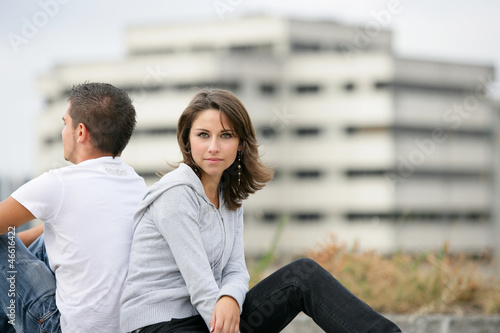 Photo: Young couple sitting back to back Young couple sitting back to back
