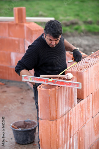 Photo: bricklayer erecting red brick wall bricklayer erecting red brick wall