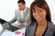 businesswoman standing in front of a colleague with laptop