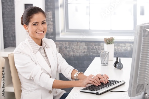 Photo: Happy office girl working on computer Happy office girl working on computer