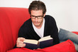 Junger Mann beim Lesen auf dem Sofa