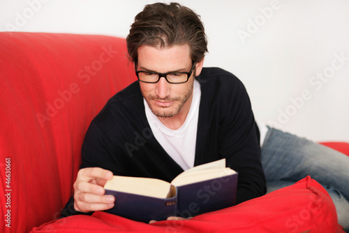 Photo: Junger Mann beim Lesen auf dem Sofa Junger Mann beim Lesen auf dem Sofa