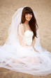 Beautiful bride with a long veil on the beach at sunset