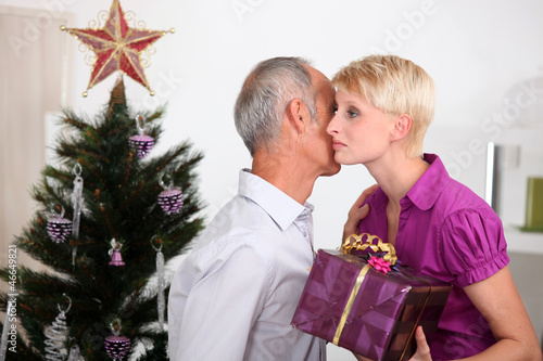 Photo: Father giving daughter Christmas present Father giving daughter Christmas present