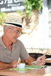 Elderly man sat drinking coffee on terrace