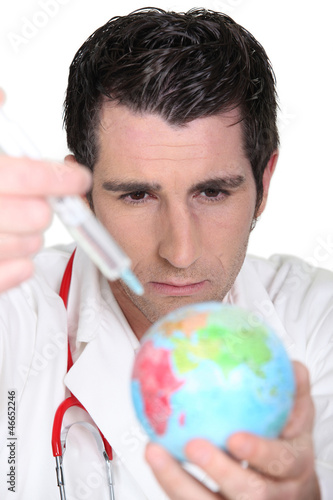 Photo: Doctor using syringe on a globe Doctor using syringe on a globe