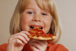 Pequeña niña comiendo pizza.