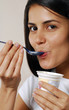 Joven mujer comiendo yogurt.