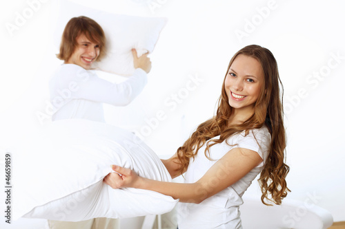 Photo: Young couple fighting with pillows Young couple fighting with pillows