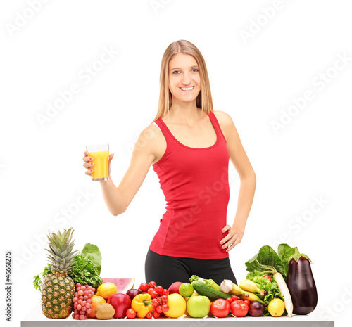 Photo: Female athlete refreshing with juice, behind a table full of foo Female athlete refreshing with juice, behind a table full of foo