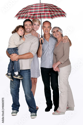 Photo: Smiling family under an umbrella Smiling family under an umbrella