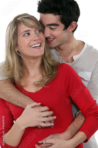Photo: young happy couple embracing against studio background young happy couple embracing against studio background