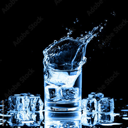 Photo: Close up view of the splash in glass with water on black Close up view of the splash in glass with water on black