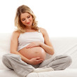 A young blond pregnant woman sitting in indoor clothes