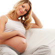 A young blond pregnant woman sitting in indoor clothes