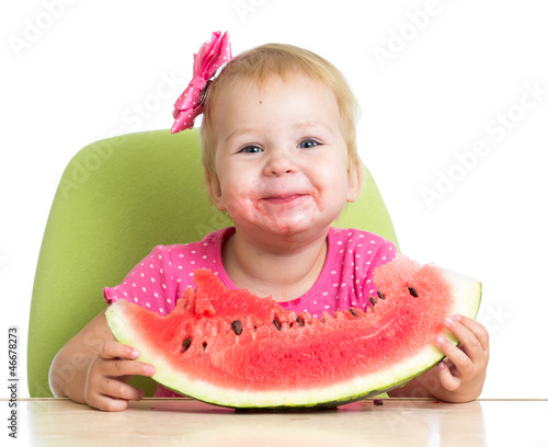 Photo: Little girl eating watermelon at table Little girl eating watermelon at table