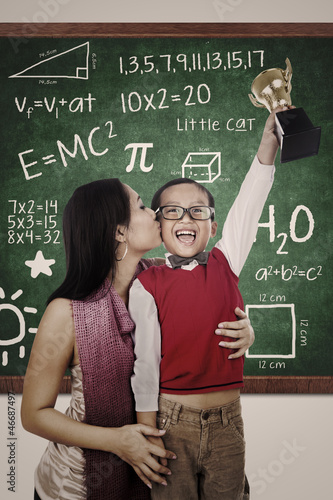 Photo: Preschooler wins Math competition holding trophy kiss by mum Preschooler wins Math competition holding trophy kiss by mum