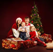 Photo: Christmas family of four persons and fir tree with gift boxes Christmas family of four persons and fir tree with gift boxes