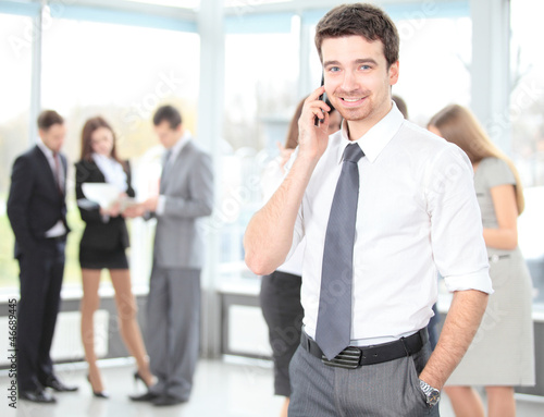 Photo: A young handsome business man on phone at office building A young handsome business man on phone at office building