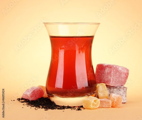 Photo: glass of Turkish tea and rahat Delight, on beige background glass of Turkish tea and rahat Delight, on beige background