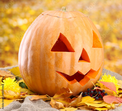 Photo: halloween pumpkin and autumn leaves, on yellow background halloween pumpkin and autumn leaves, on yellow background