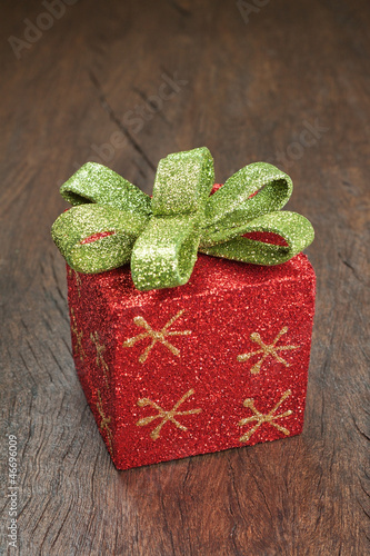Photo: Christmas gift box with a bow on a wooden texture. Christmas gift box with a bow on a wooden texture.