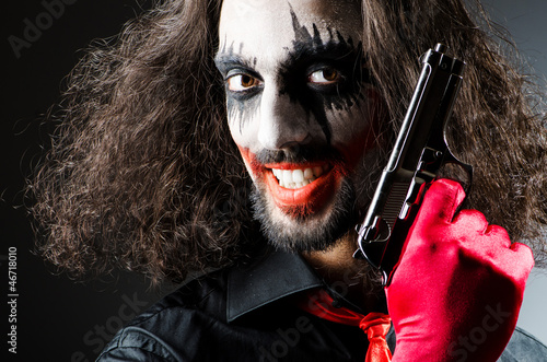 Photo: Evil clown with gun in dark room Evil clown with gun in dark room