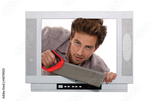 Photo: Man with a saw inside a television set Man with a saw inside a television set