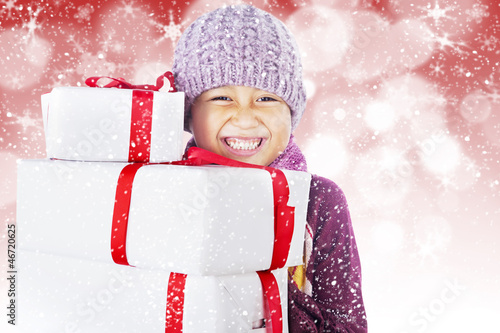 Photo: Happy boy holding white christmas boxes on defocused light Happy boy holding white christmas boxes on defocused light