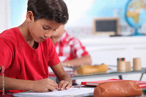 Photo: little boy focusing on his work in classroom little boy focusing on his work in classroom