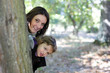 Mum and daughter hiding behind a tree