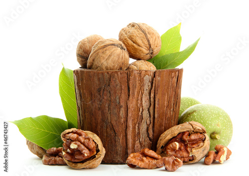 Photo: walnuts with green leaves in woooden vase, isolated on white walnuts with green leaves in woooden vase, isolated on white