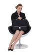 Serious businesswoman sitting with a briefcase