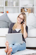 frau mit laptop telefoniert zu hause
