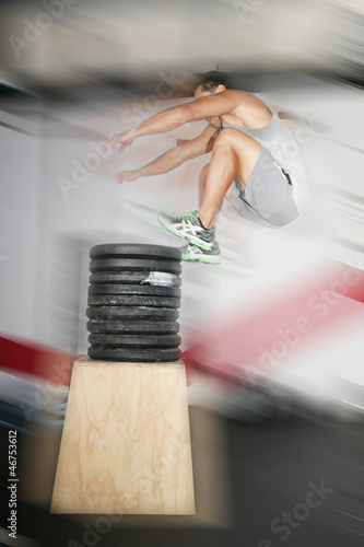 Photo: Athletic man jumping over a lot of weights Athletic man jumping over a lot of weights