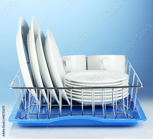 Photo: clean dishes on stand on blue background clean dishes on stand on blue background