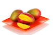 Ripe appetizing mango on red plate isolated on white