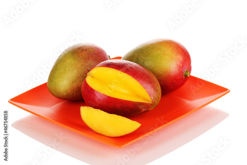 Photo: Ripe appetizing mango on red plate isolated on white Ripe appetizing mango on red plate isolated on white