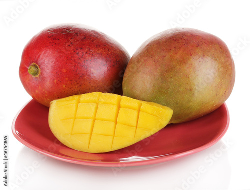 Photo: Ripe appetizing mango on red plate isolated on white Ripe appetizing mango on red plate isolated on white