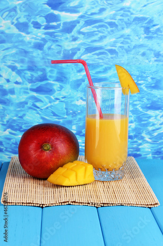 Photo: Ripe appetizing mango on woven napkin on water background Ripe appetizing mango on woven napkin on water background