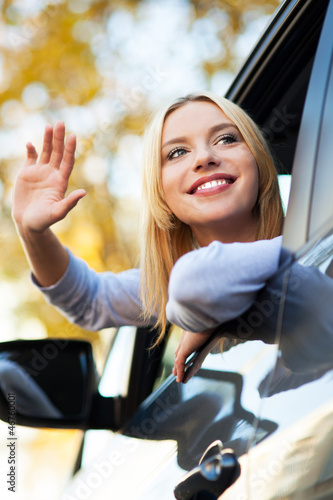 Photo: Woman waving from car window Woman waving from car window