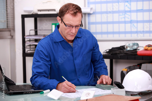 Photo: Builder working on paperwork in an office Builder working on paperwork in an office