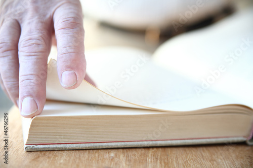 Photo: a man turns the pages of a large book a man turns the pages of a large book