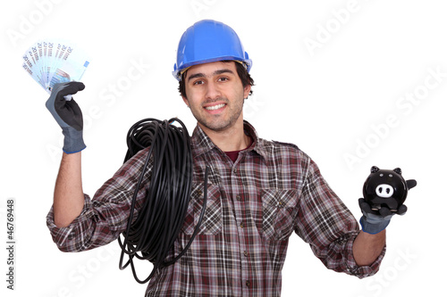 Photo: Laborer holding bills and piggy bank Laborer holding bills and piggy bank