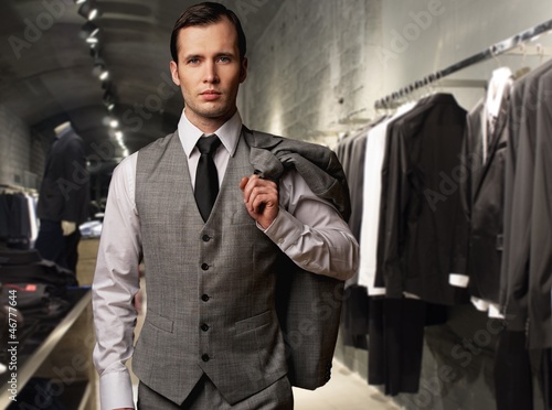 Photo: Businessman in classic vest against row of suits in shop Businessman in classic vest against row of suits in shop