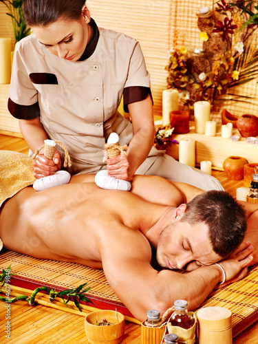Photo: Man getting herbal ball massage treatments . Man getting herbal ball massage treatments .